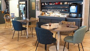 Een restaurant met een bakstenen muur, een koffieapparaat en diverse gerechten in de etalage.