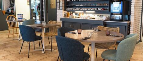 A restaurant with a brick wall, a coffee machine, and a variety of dishes on display.