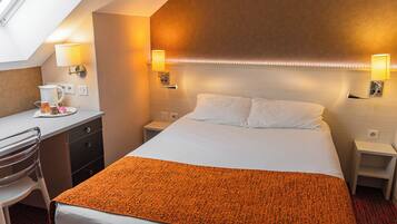A hotel room with a bed, bedside tables, a desk, and a chair.