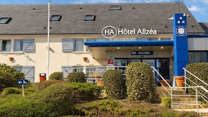 Een hotel met een blauwe ingang, een bordje voor de lobby en een klokkentoren.