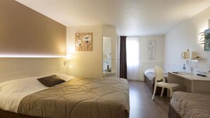 Een hotelkamer met een groot bed, een bureau en een stoel. Er hangt een spiegel aan de muur en een schilderij boven het bed.