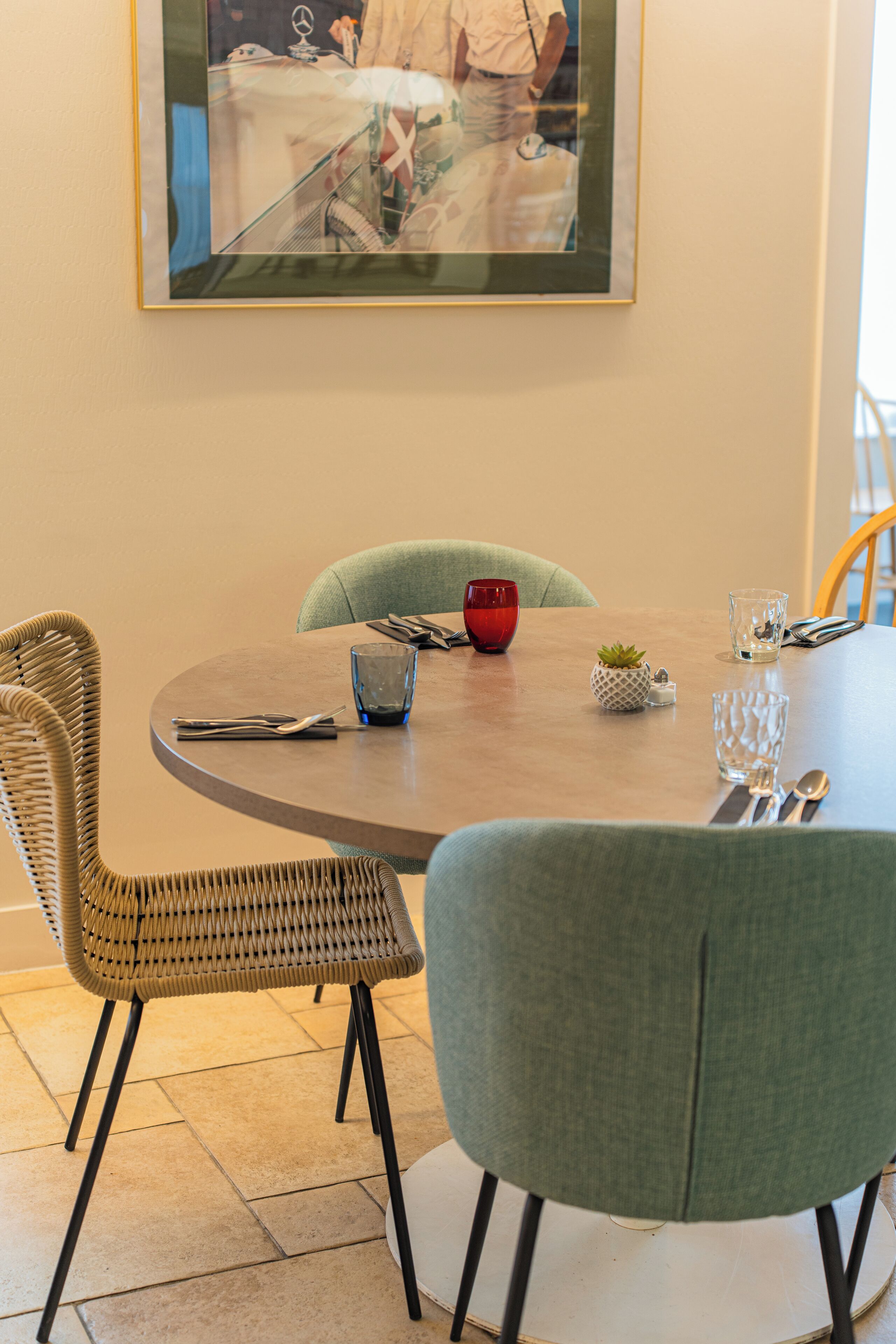 A dining area with a round table, two chairs, a red bowl, and a small plant.