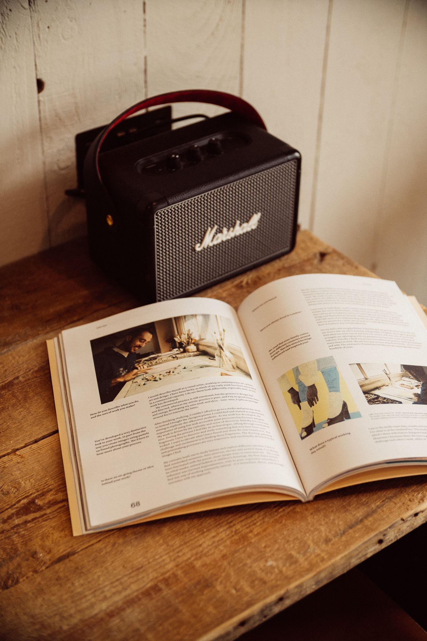 An open book with text and images on a wooden surface, next to a black Marshall amplifier.