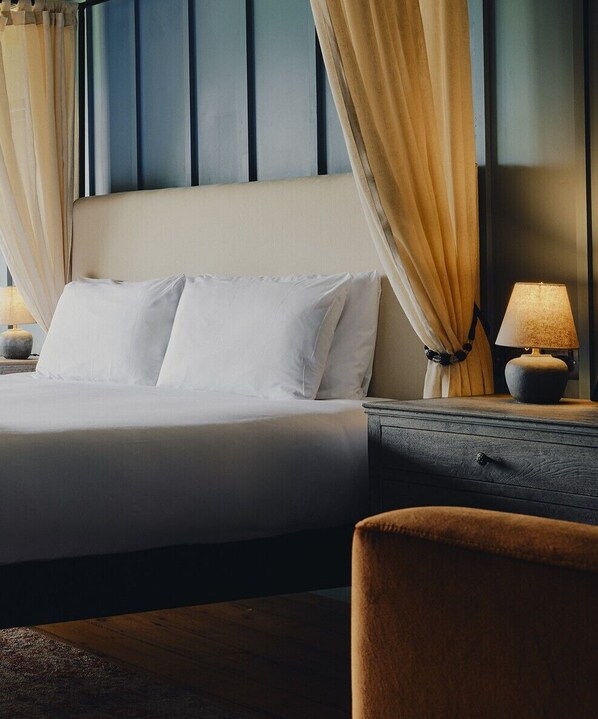 A neatly made bed with white linens, a bedside table with a lamp, and a chair. - Glasson LakeHouse (Athlone)