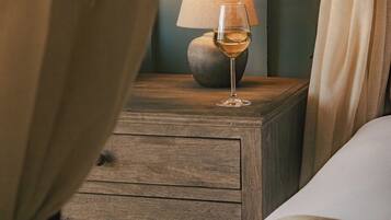 Ein Nachttisch aus Holz mit einer Lampe und einem Glas Weißwein.