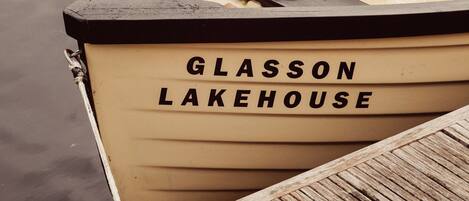 A wooden boat with the name "Glasson Lakehouse" on its side, docked at a wooden pier.