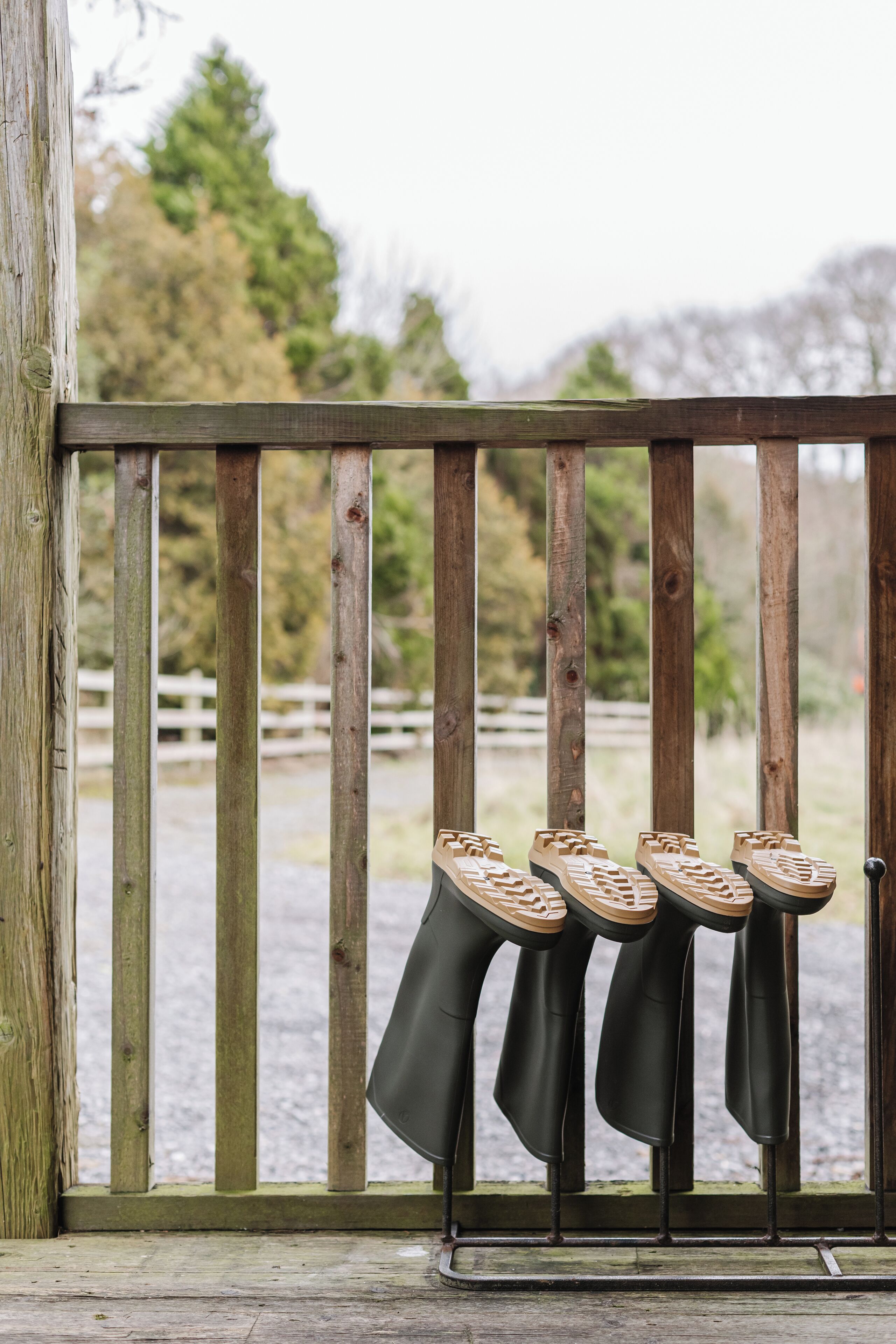 Une rambarde en bois avec un porte-chaussures en métal contenant plusieurs paires de chaussures.