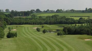 A golf course with well-manicured fairways, sand bunkers, and a pond.