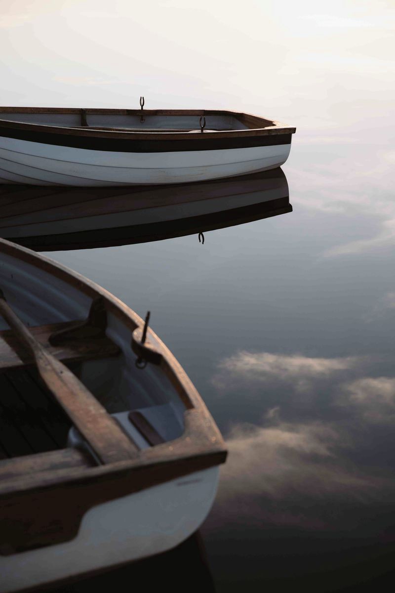 Two boats, one on top of the other, with a cloudy sky in the background.