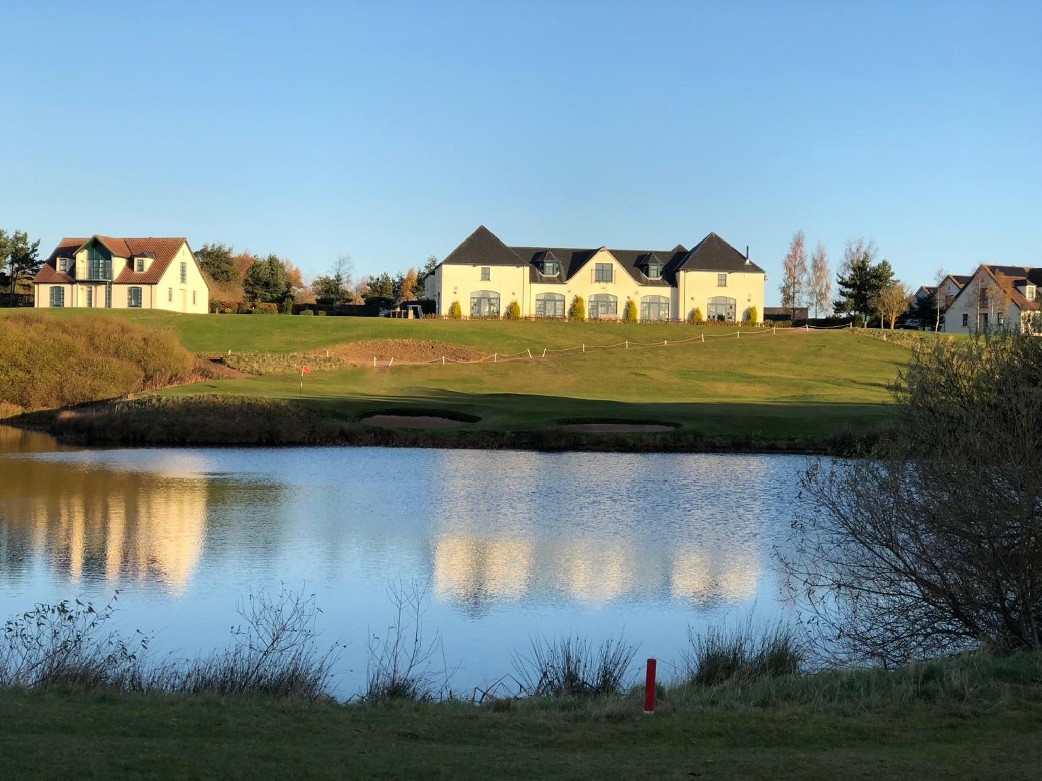 Un barrio residencial con casas, un estanque y un campo de golf.