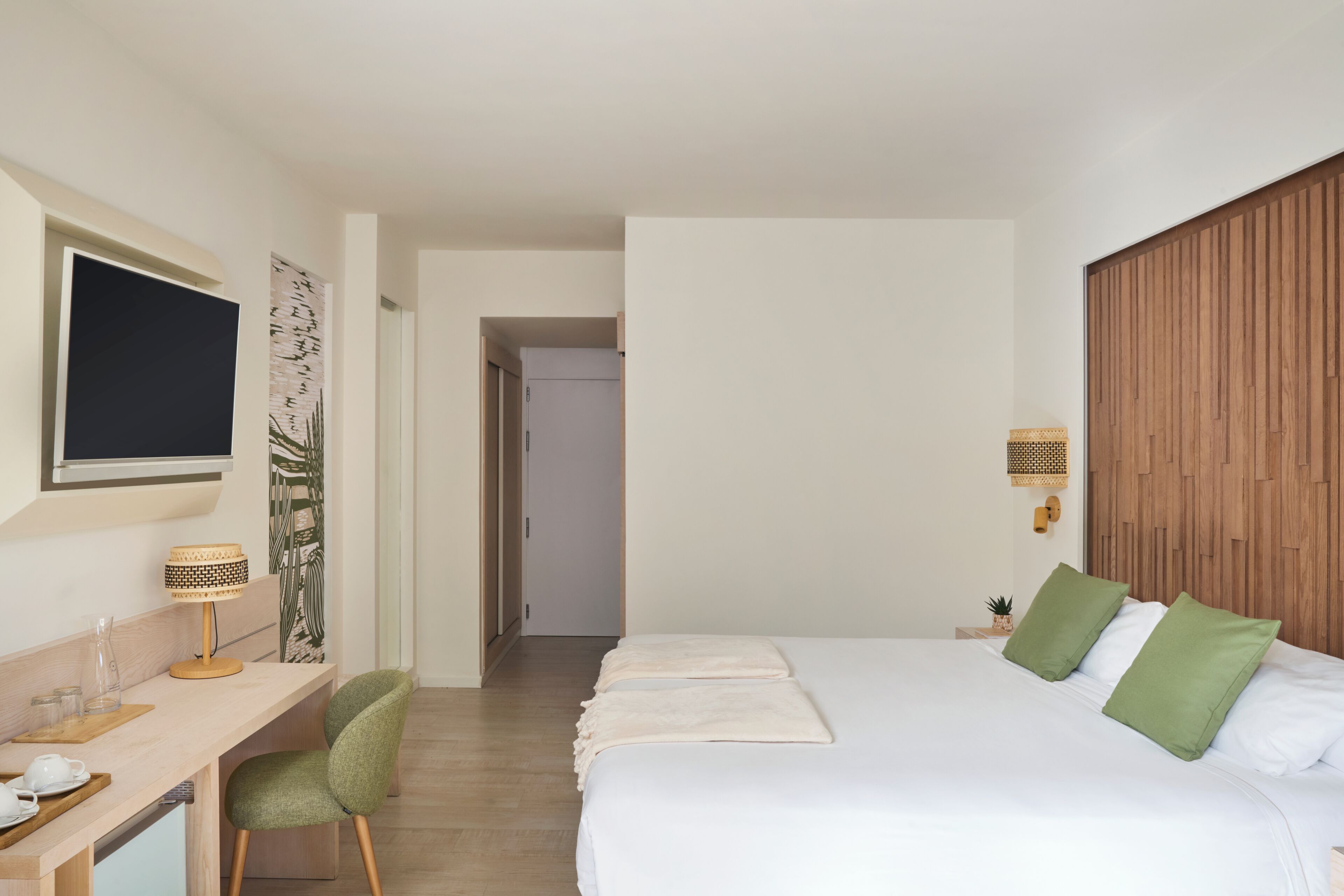 Habitación de hotel con cama, escritorio, silla, televisor y armario de madera.