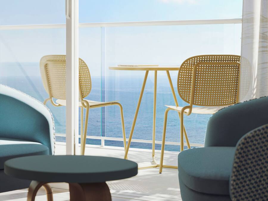 Ein Balkon mit zwei Stühlen und einem Tisch mit Blick auf das Meer.