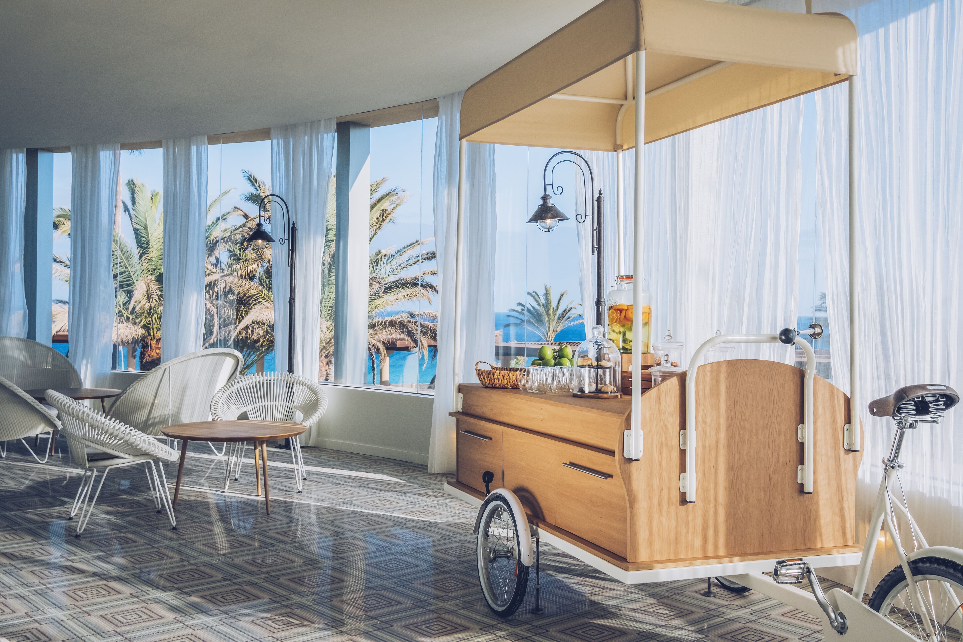 Une pièce moderne avec de grandes fenêtres, un meuble en bois, un vélo et une chaise.