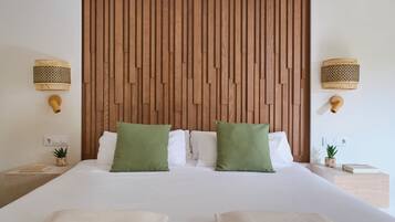 A neatly made bed with two green pillows, a wooden headboard, and two wall-mounted lamps.