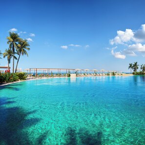 A clear blue pool with lounge chairs and umbrellas, surrounded by palm trees and a clear sky. - Iberostar Selection Fuerteventura Palace (Pajara)