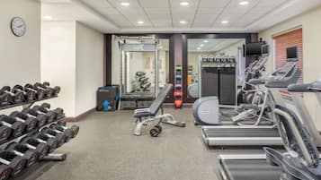 Un gimnasio con cintas de correr, mancuernas y máquinas de pesas.