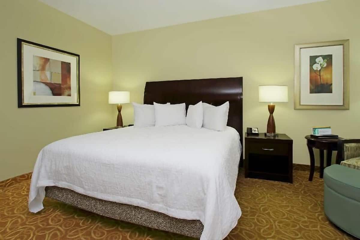 A hotel room with a large bed, two bedside tables with lamps, a small desk, and a chair.