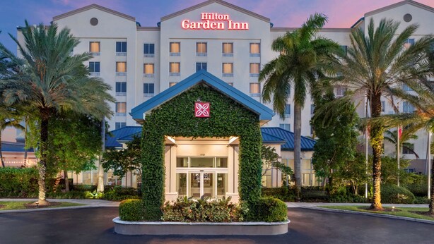 A Hilton Garden Inn with a distinctive entrance covered in greenery, surrounded by palm trees and well-maintained landscaping. - Hilton Garden Inn Miami Airport West (Miami)