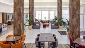 A spacious lobby with high wooden pillars, comfortable seating areas, and a central coffee table. - Hilton Garden Inn Miami Airport West (Miami)