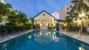 A hotel with a swimming pool, palm trees, and lounge chairs. - Hilton Garden Inn Miami Airport West (Miami)
