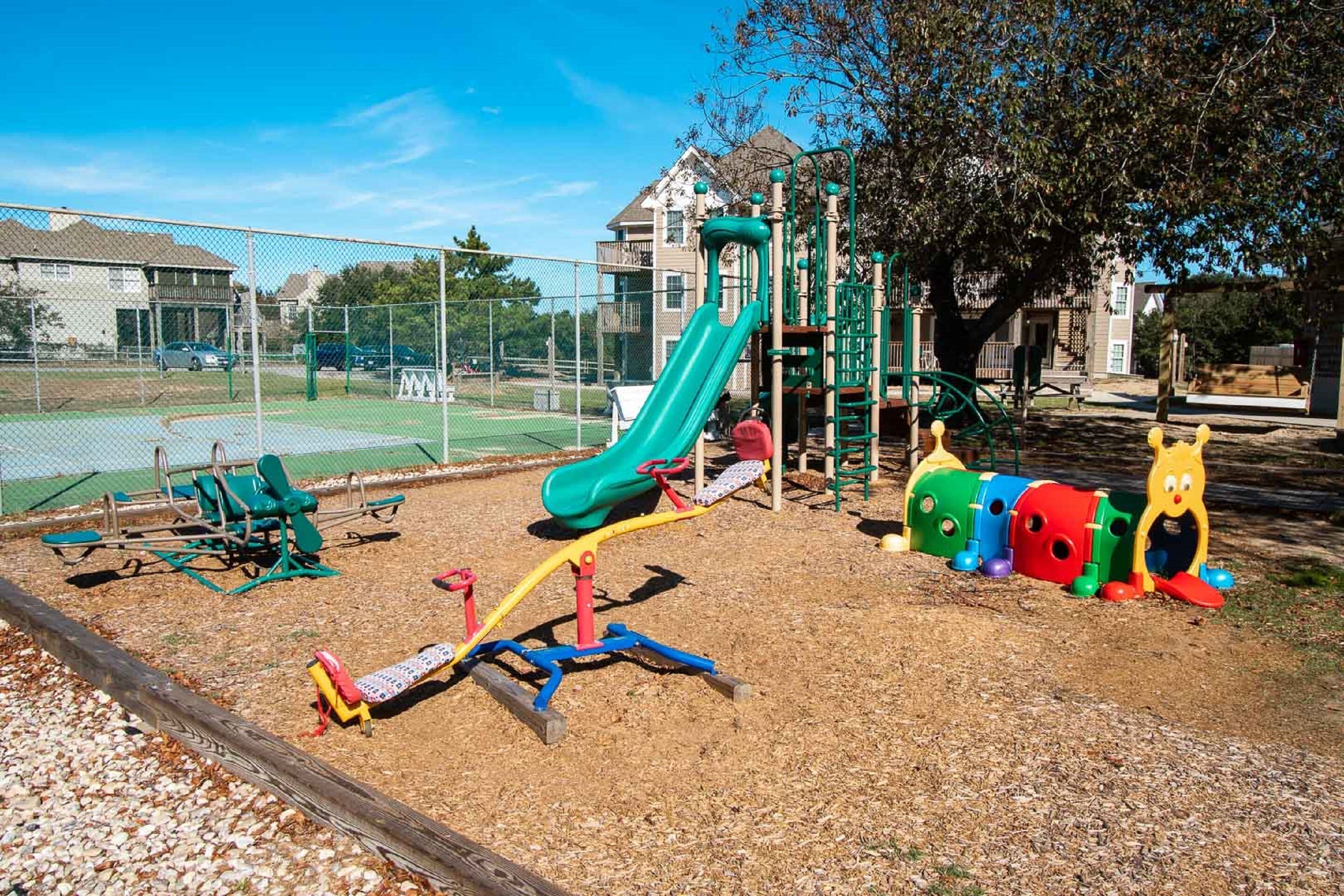 Une aire de jeux avec un toboggan, des balançoires et une structure d’escalade.