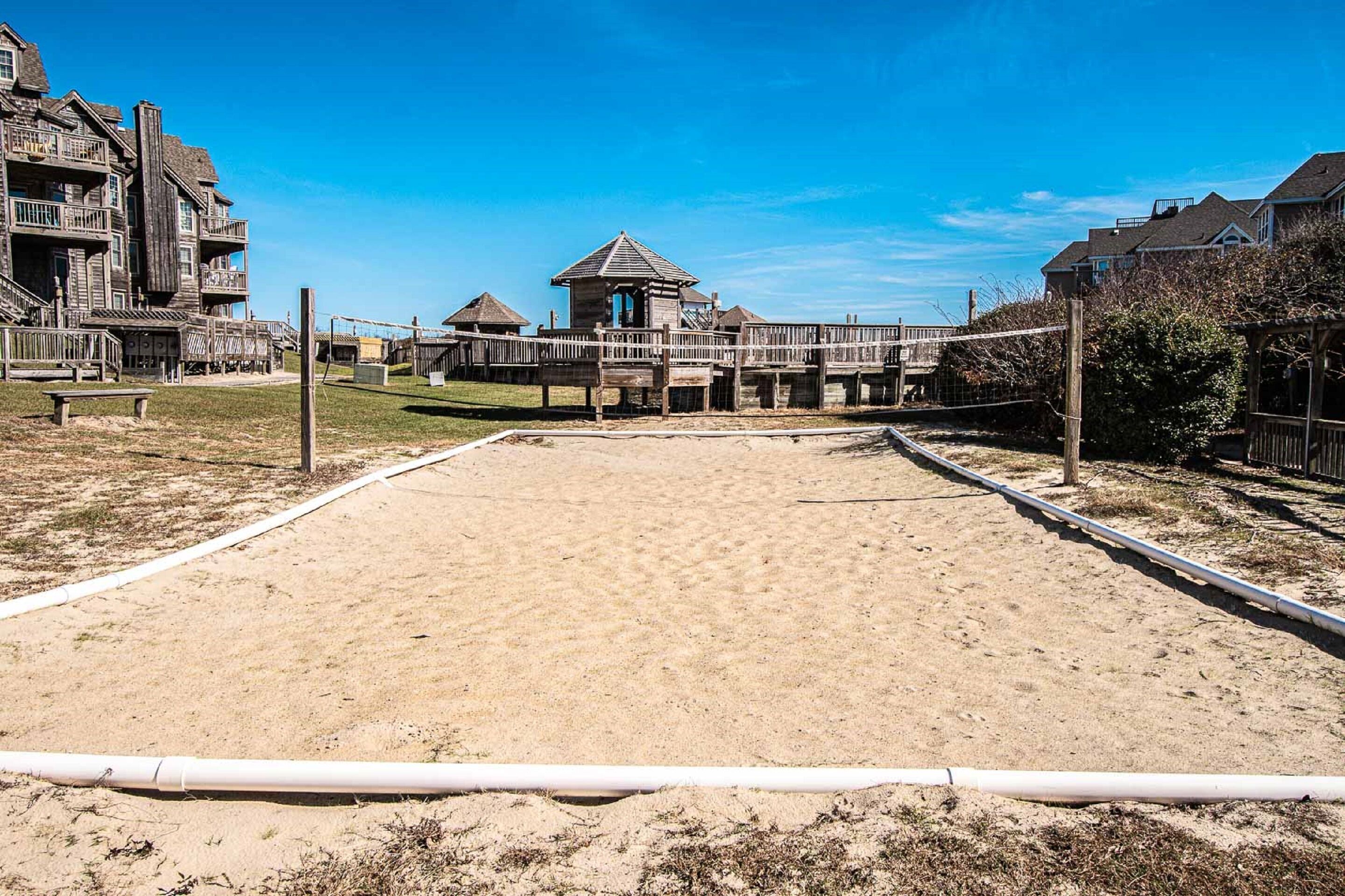 Una cancha de voleibol de playa con arena, estructuras de madera y un pequeño pabellón.
