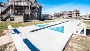 A boardwalk with a shuffleboard court, wooden boardwalks, and a building with multiple balconies. - Barrier Island Station (Kitty Hawk)
