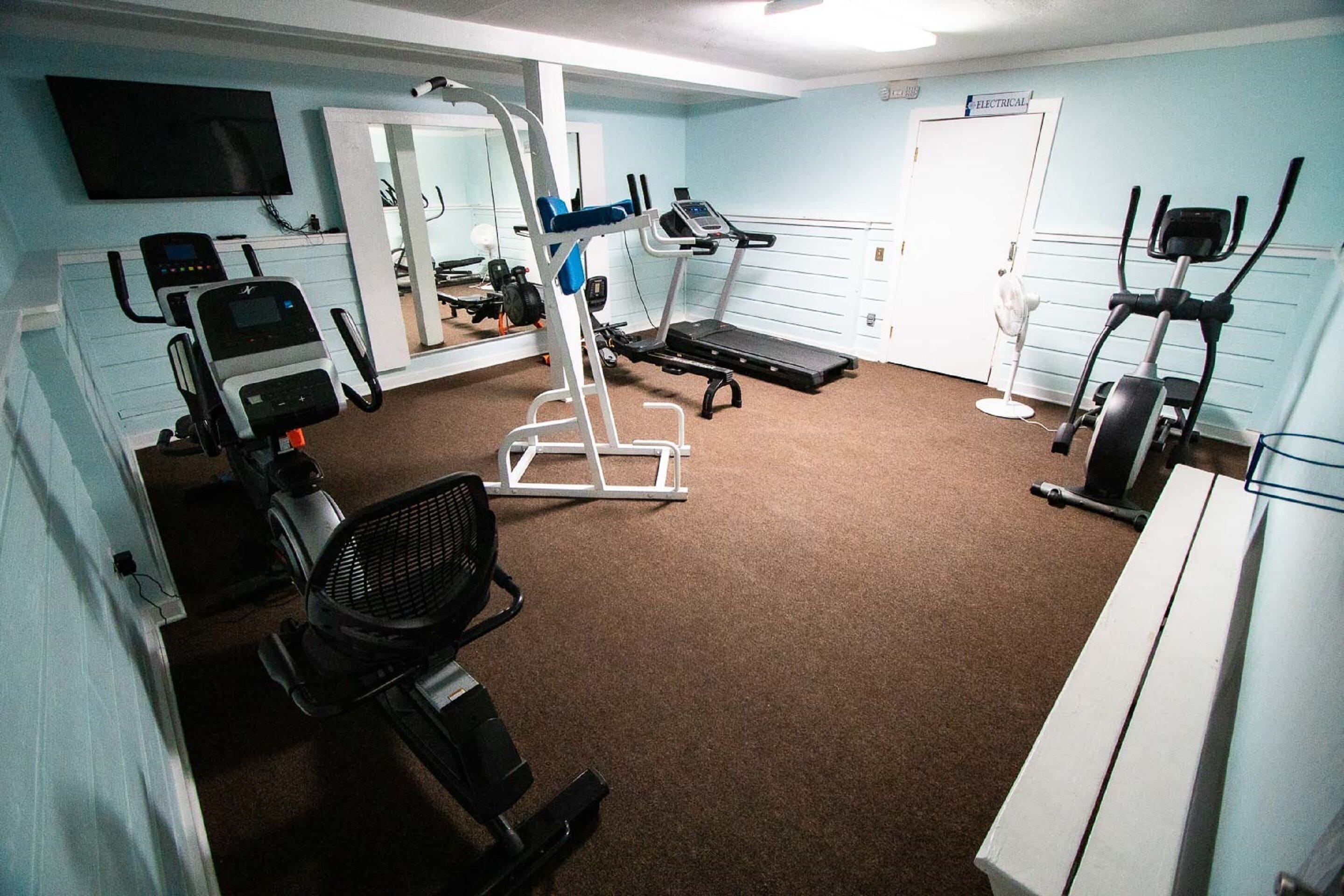 A gym with exercise equipment, a treadmill, and a mirror.