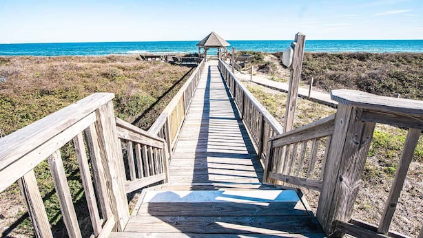 A wooden boardwalk leading to a beach with a gazebo at the end. - Barrier Island Station (Kitty Hawk)