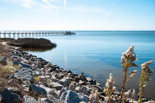 Una costa rocosa con un muelle que se adentra en aguas tranquilas.