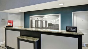 A hotel reception desk with a framed picture of silos and the word "enjoy."