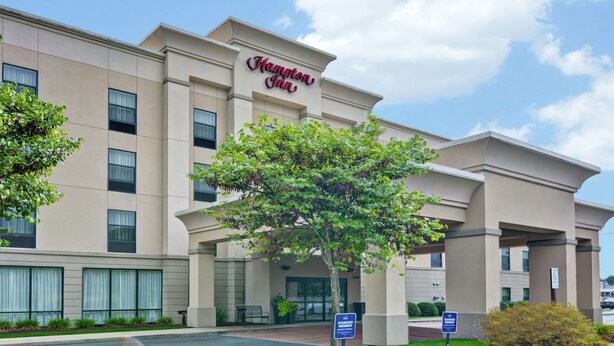 A Hampton Inn hotel with a modern facade, large windows, and a prominent entrance.