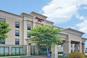 Un hotel Hampton Inn con fachada moderna, amplias ventanas y una entrada destacada.