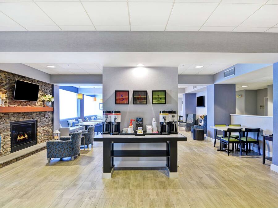 Um lobby moderno com lareira, área de estar, espaço para café e área de refeições.