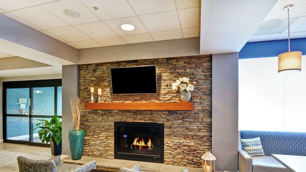 A modern lobby with a stone fireplace, comfortable seating, and a large TV screen.