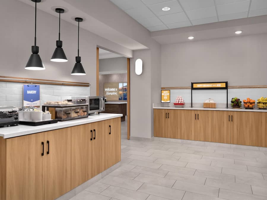 Un espace moderne dédié au petit-déjeuner, comprenant un comptoir de boulangerie, un four à micro-ondes et un présentoir de fruits.