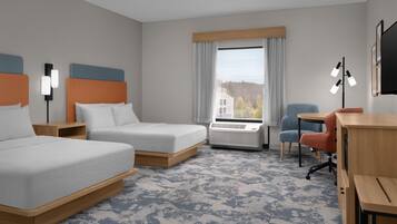 Une chambre d’hôtel avec deux lits, un bureau, une chaise, une fenêtre donnant sur un paysage agréable et un ventilateur de plafond.