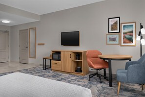 Una habitación de hotel con cama, escritorio, silla, televisión y armario.