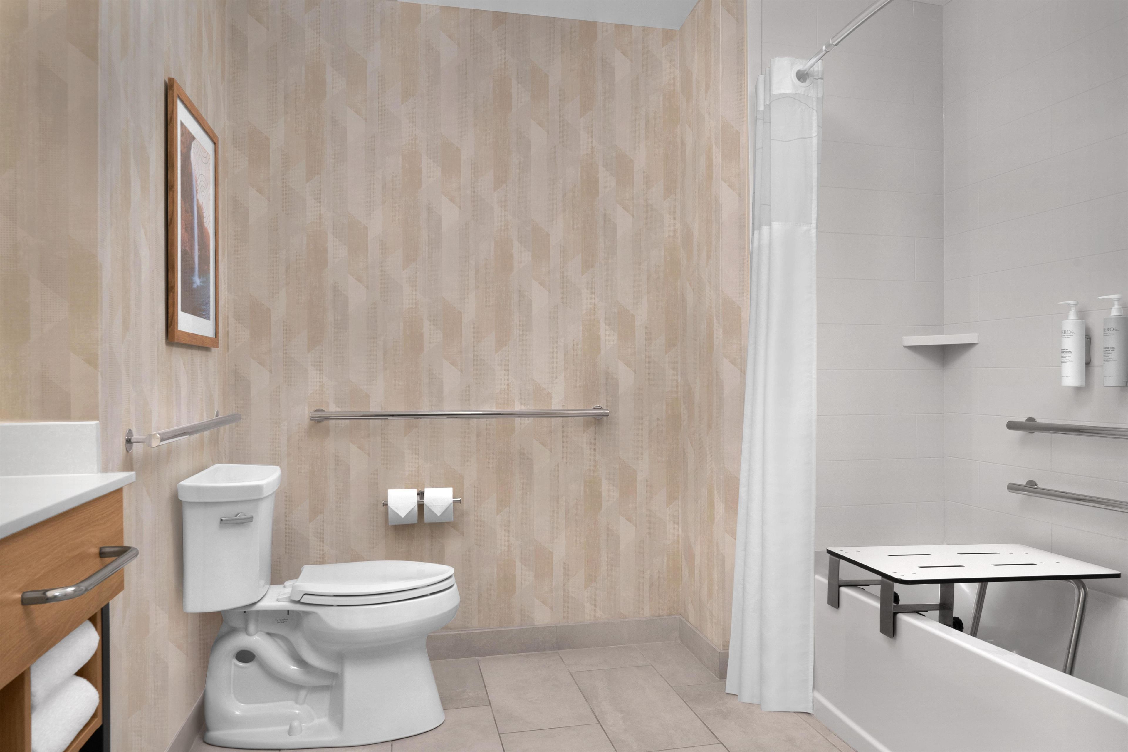 A modern bathroom with a toilet, bidet, shower, and a small vanity area.