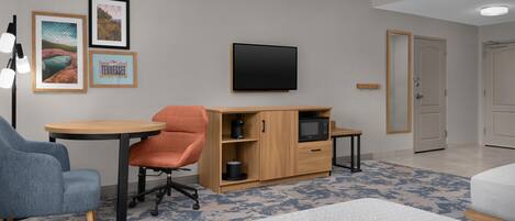 A modern room with a desk, a chair, a bed, and a television on the wall.