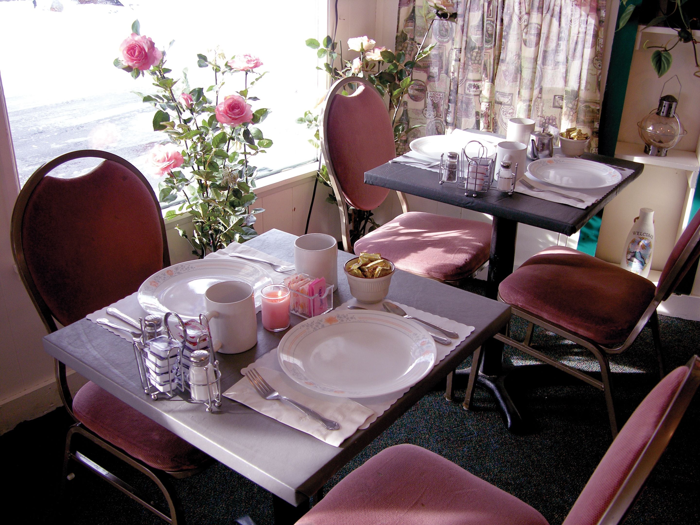 Un coin repas avec une table mise pour deux personnes, comprenant des assiettes, des couverts et une bougie.