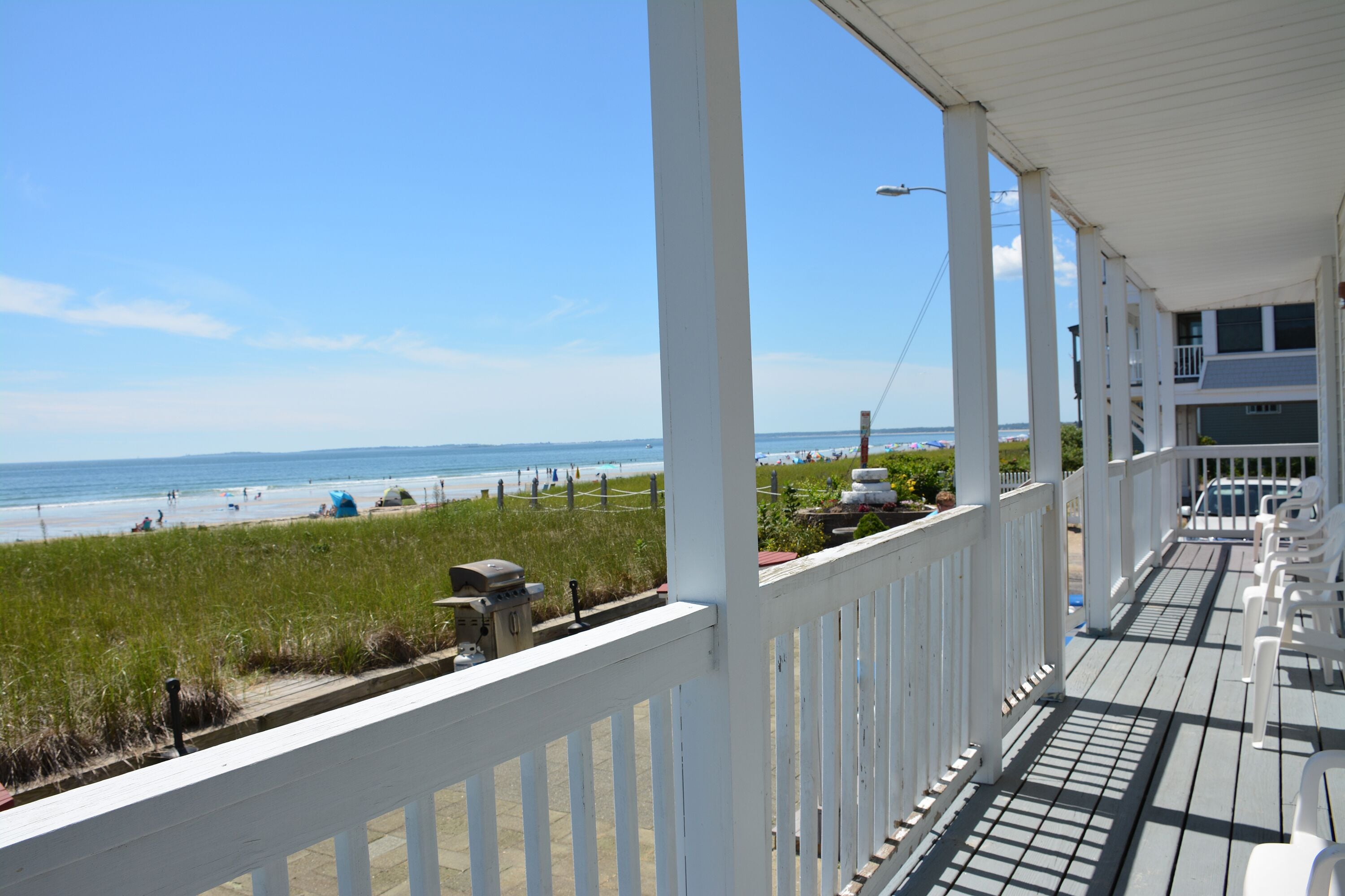 A covered porch with a view of the beach and ocean.