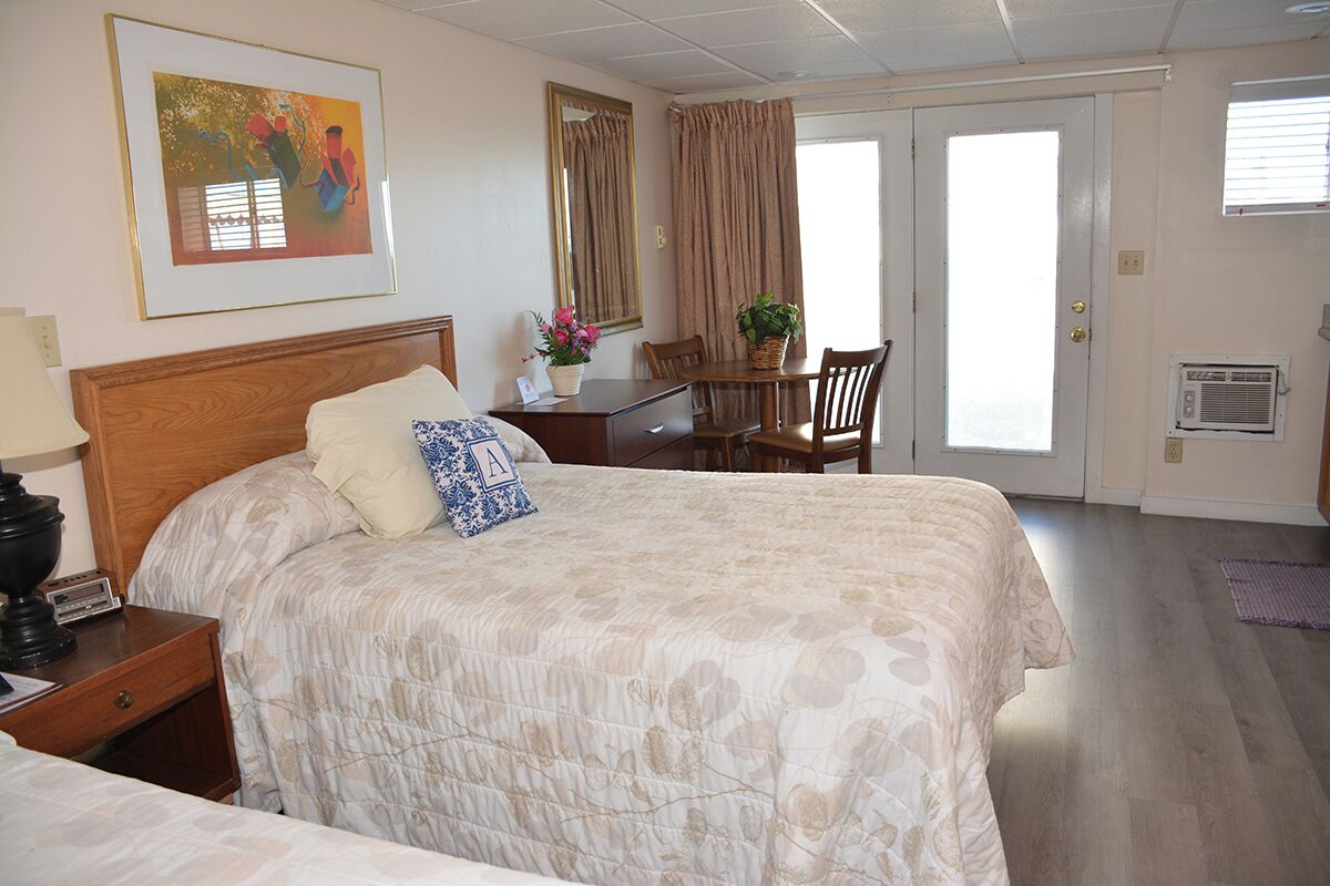 A hotel room with a large bed, a desk, a chair, a dining table, and a window.