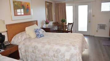 A hotel room with a large bed, a desk, a chair, a dining table, and a window.