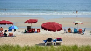 Egy strand, ahol több napernyő és strandágy található.