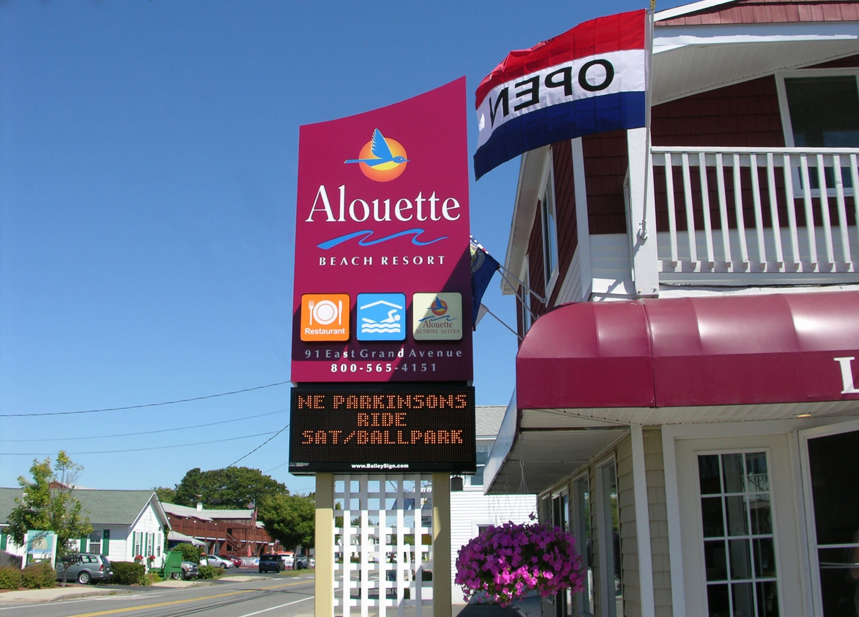 A building with a sign for Alouette Beach Resort, including amenities like a restaurant and sunbathing.