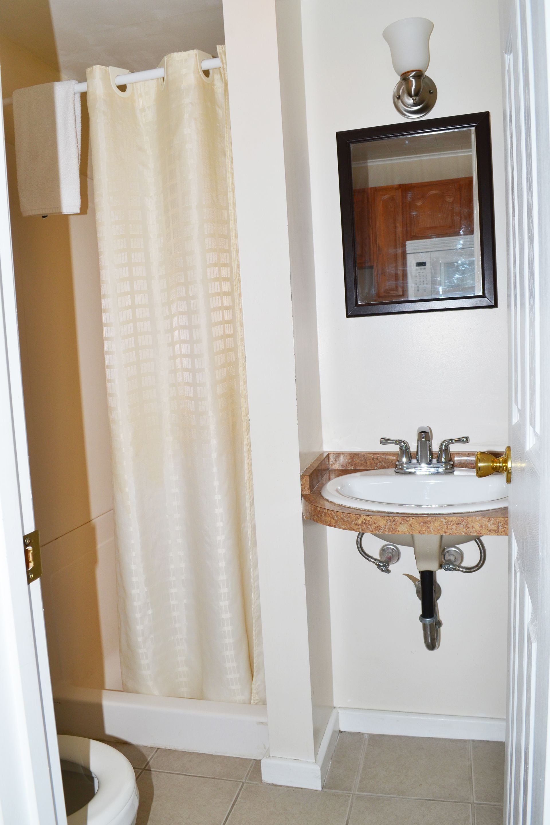 A bathroom with a shower curtain, a sink with a mirror above it, and a toilet.