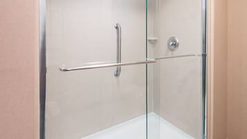 A glass-enclosed shower with a handrail and a control panel.