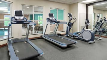 A gym with treadmills, stationary bikes, and a mirrored wall.