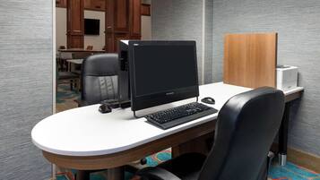 Une chambre d’hôtel équipée d’un bureau rond, d’un ordinateur, d’un clavier, d’une souris et d’une chaise.